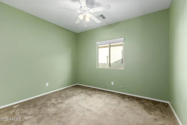 an empty room with a window and a fan