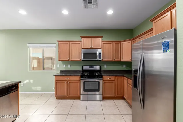 a kitchen with stainless steel appliances granite countertop a refrigerator and a stove top oven