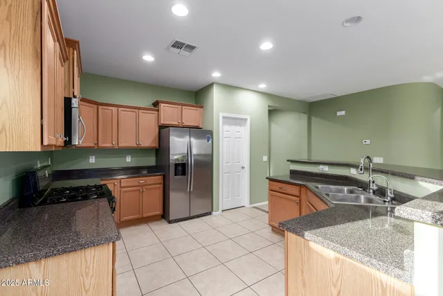 a kitchen with stainless steel appliances granite countertop a sink and a refrigerator