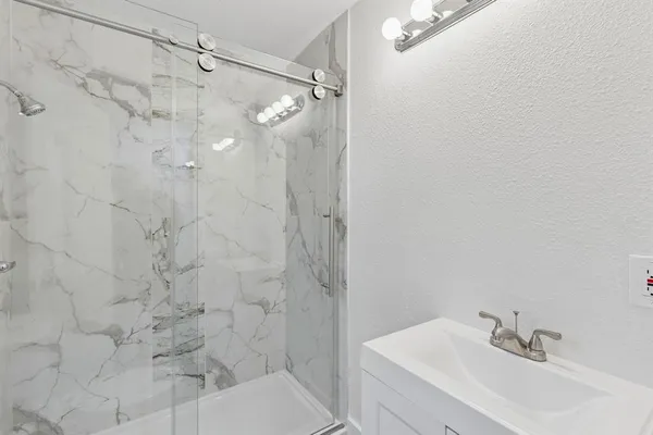 a bathroom with a sink shower and a mirror