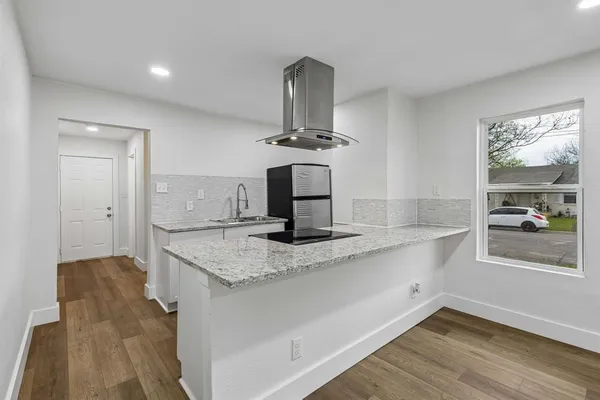 a kitchen with kitchen island stainless steel appliances a sink and wooden floor