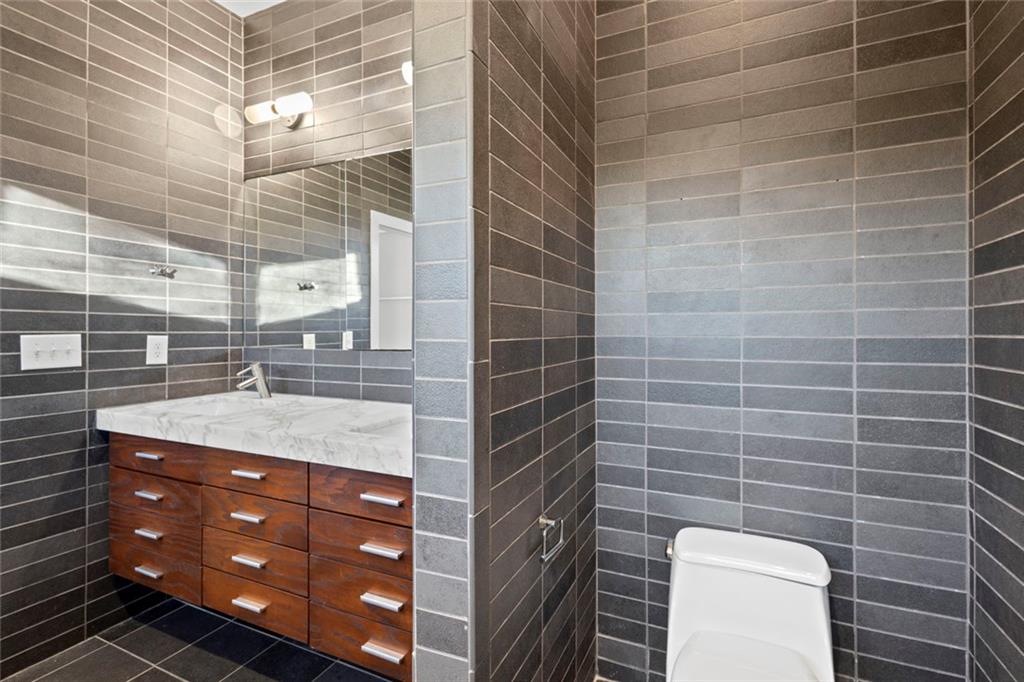 935 Custer Avenue Southeast Atlanta, GA 30316 - Photo 11 of 24 a bathroom with a granite countertop sink a toilet and blue shower
