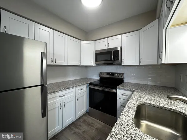 a kitchen with granite countertop a sink stove and refrigerator