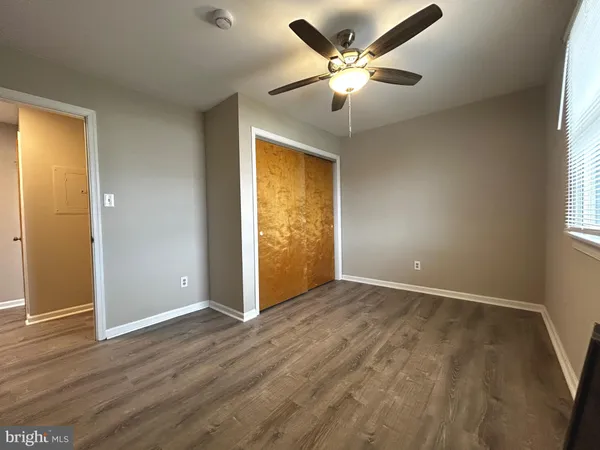 an empty room with wooden floor fan and windows