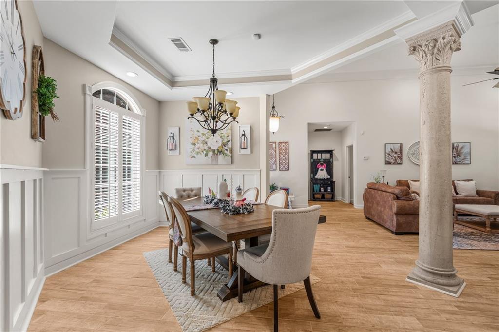 642 Nuckols Road Seale, AL 36875 - Photo 9 of 48 Tray ceiling with crown molding, wood-finish flooring, wainscoting, arched window with plantation shutters, and a decorative column