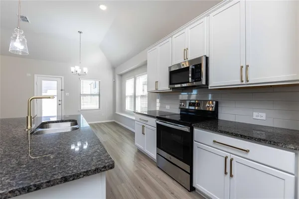 a kitchen with stainless steel appliances granite countertop a sink a stove and a microwave oven