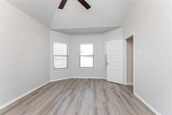 an empty room with wooden floor chandelier fan and windows