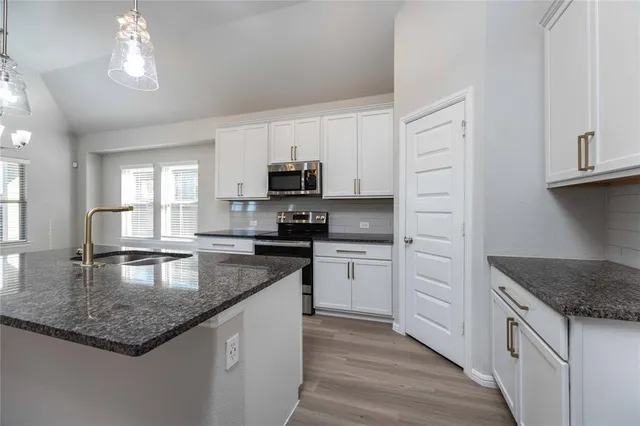 a kitchen with stainless steel appliances granite countertop a sink dishwasher stove and refrigerator