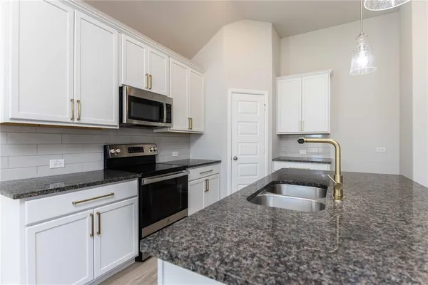 a kitchen with granite countertop a sink dishwasher stove and cabinets