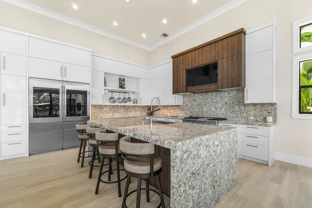 a kitchen with stainless steel appliances kitchen island granite countertop a table chairs sink and cabinets