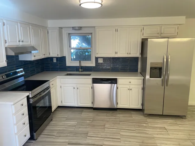 a kitchen with white cabinets stainless steel appliances and sink