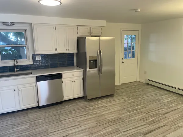 a kitchen with granite countertop white cabinets and refrigerator