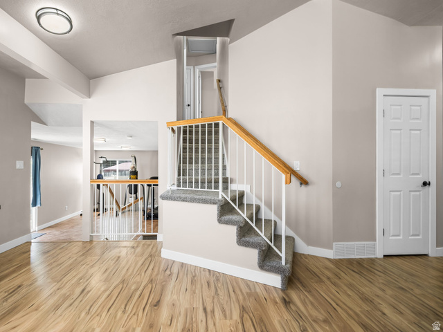 392 West Bricker Road Draper, UT 84020 - Photo 11 of 33 Interior staircase featuring carpeted treads, white balusters, and a natural wood handrail