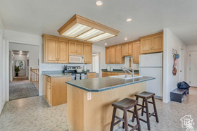 19 East Southfield Road Spanish Fork, UT 84660 - Photo 64 of 74 Kitchen with a breakfast bar, light brown cabinets, white appliances, a center island with sink, and recessed lighting