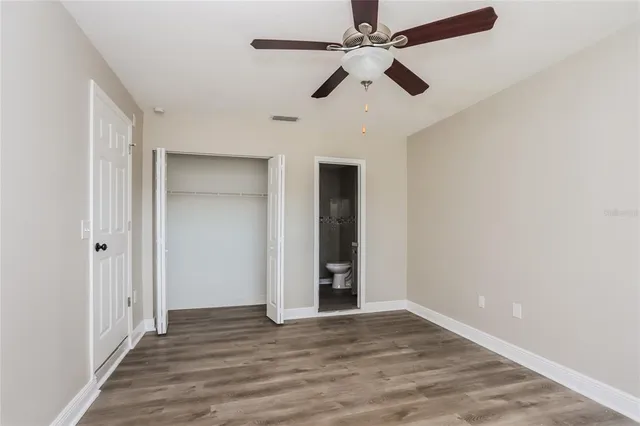 an empty room with wooden floor fan and windows