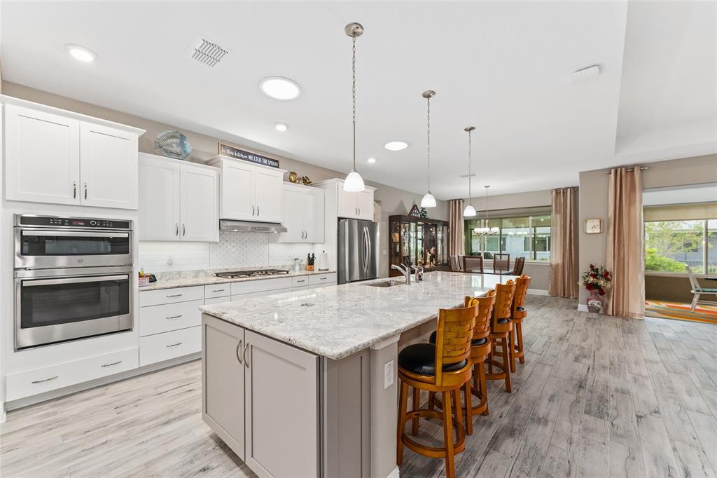 8290 Southwest 92nd Circle Ocala, FL 34481 - Photo 12 of 46 a open kitchen with stainless steel appliances granite countertop a stove top oven a refrigerator a sink and white cabinets with wooden floor