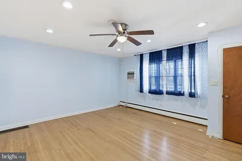 an empty room with wooden floor a ceiling fan and windows