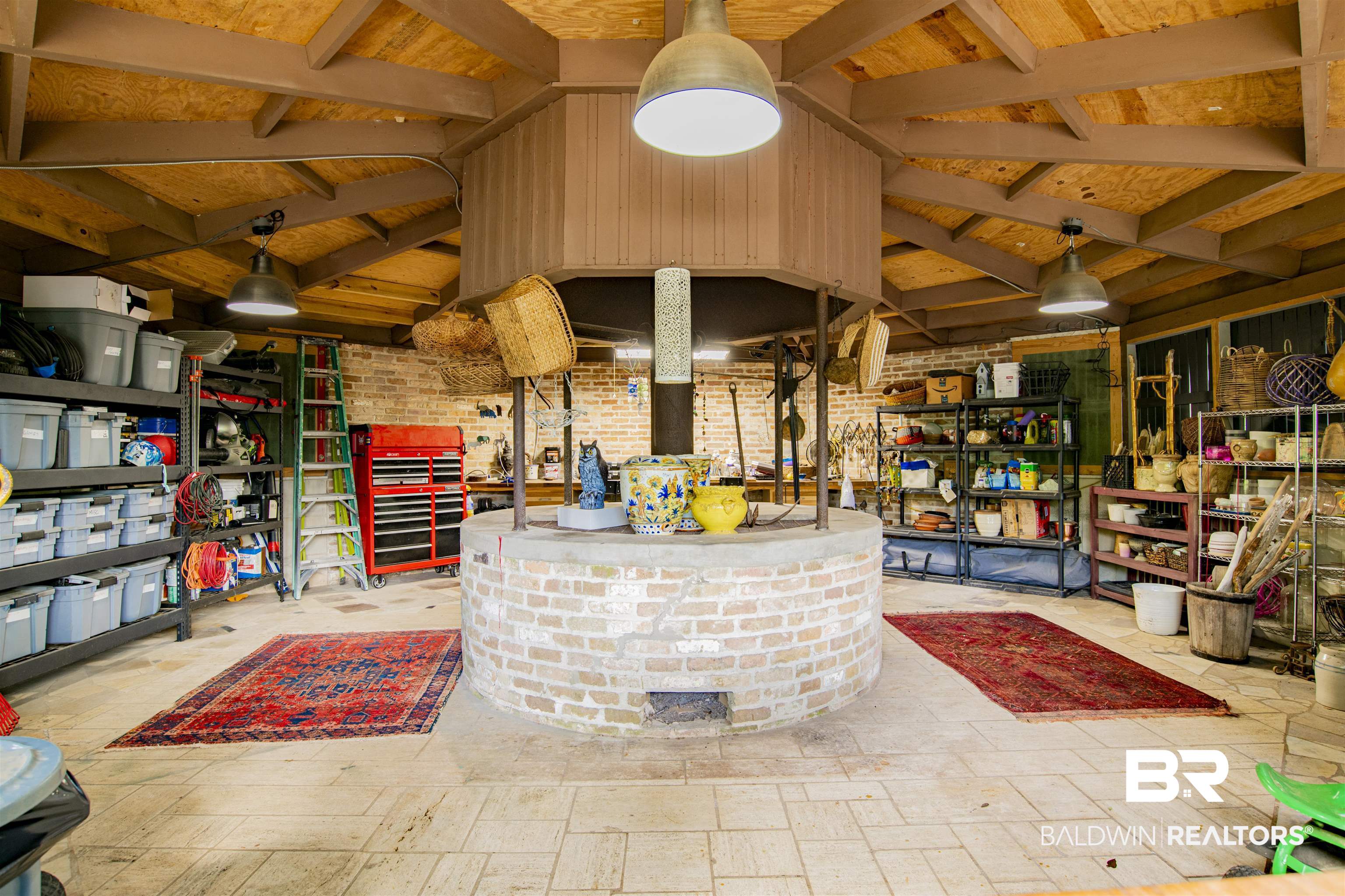 809 Bernard Circle Mobile, AL 36693 - Photo 59 of 75 Spacious workshop featuring a central brick structure, exposed wood ceiling with beams, brick accent walls, and industrial pendant lighting