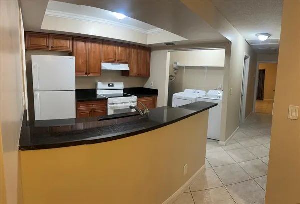a kitchen with kitchen island granite countertop a sink a stove and a refrigerator