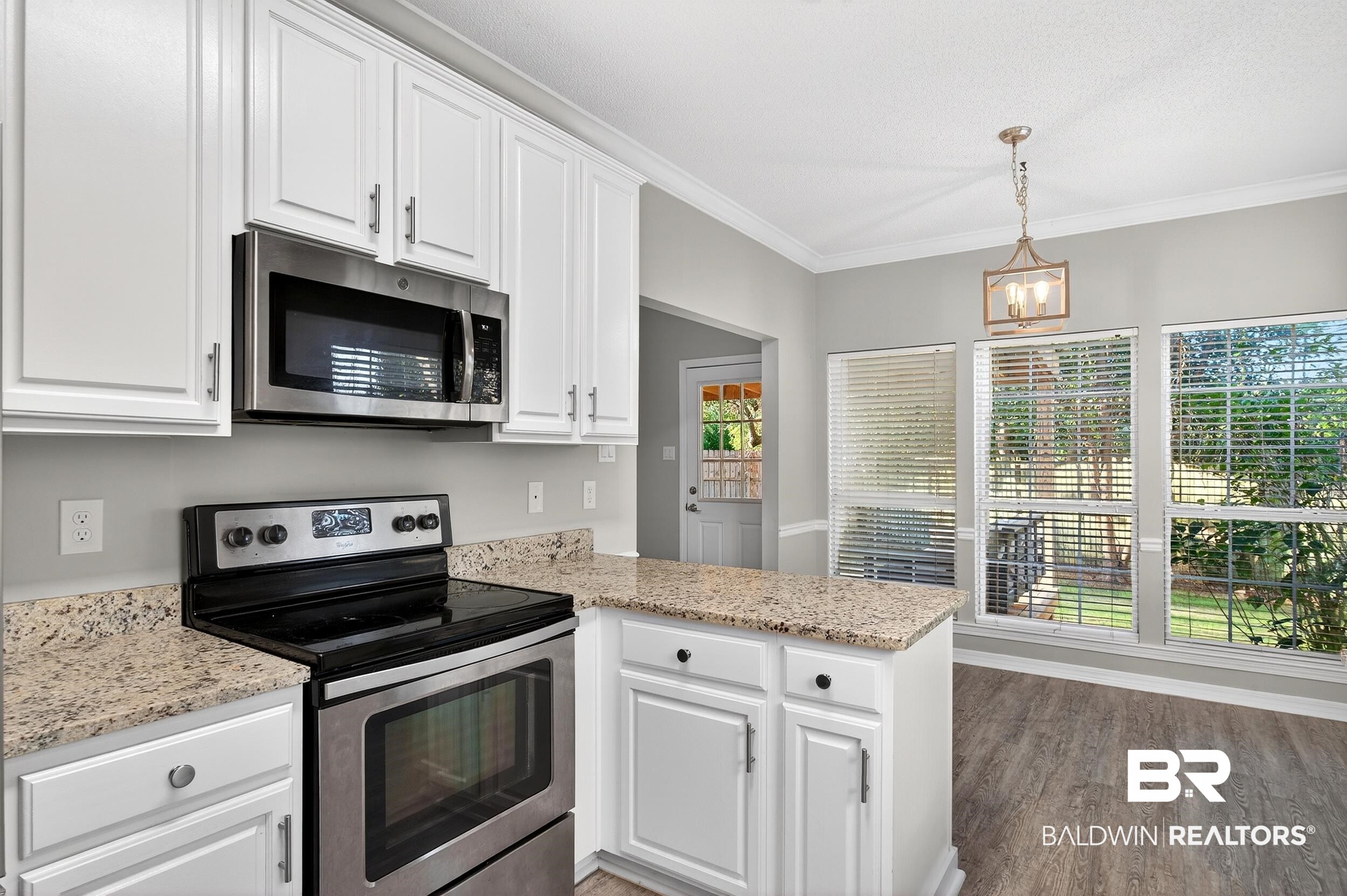 7050 Highpointe Place West Daphne, AL 36527 - Photo 20 of 66 Kitchen featuring stainless steel appliances, a peninsula, white cabinetry, light stone countertops, and crown molding