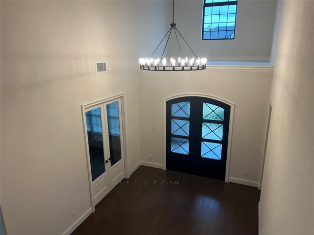 a view of a big room with wooden floor a chandelier windows and a kitchen view