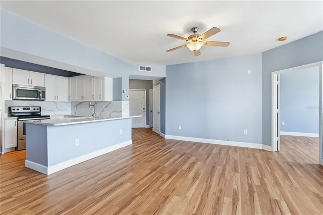 a view of kitchen with stainless steel appliances granite countertop a refrigerator a sink dishwasher a stove with wooden floor and cabinets