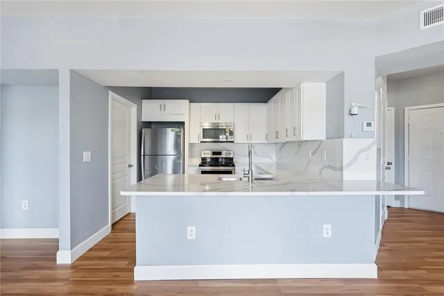 a kitchen with stainless steel appliances white cabinets and a stove top oven
