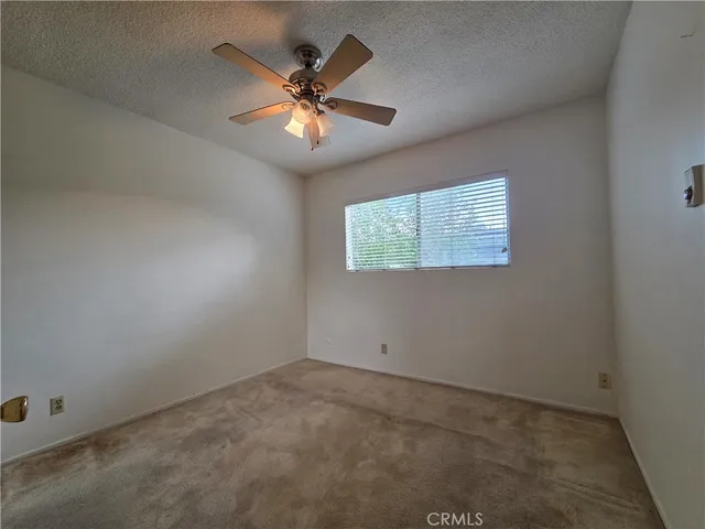 an empty room with a ceiling fan and a window