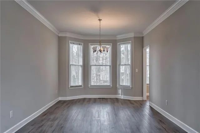 an empty room with a chandelier fan and windows