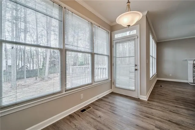 an empty room with wooden floor mirror and windows