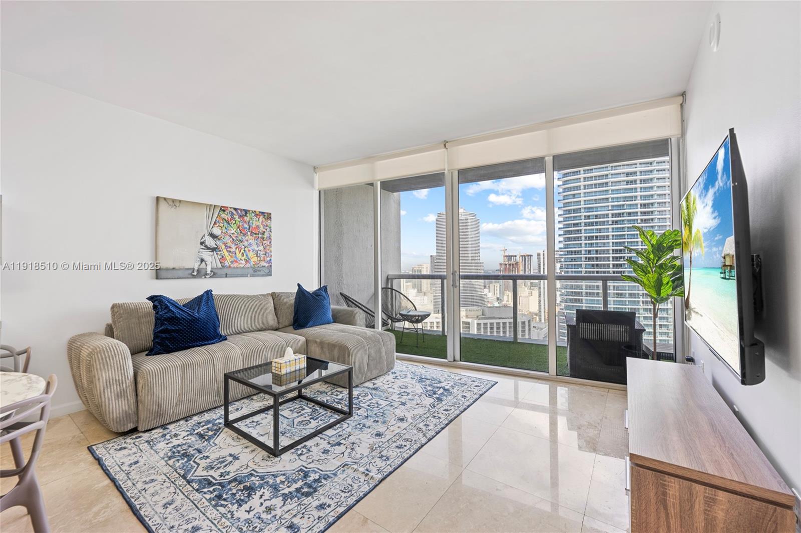 485 Brickell Avenue, Unit 3503 Miami, FL 33131 - Photo 9 of 23 a living room with furniture a flat screen tv and a floor to ceiling window