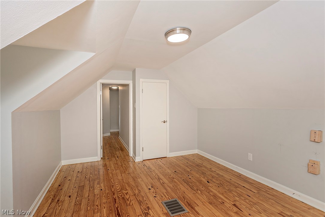 3719 Walter Road North Olmsted, OH 44070 - Photo 32 of 35 Room featuring sloped ceilings, wood-finish flooring, a flush-mount ceiling light, a white door, and light gray wall paint