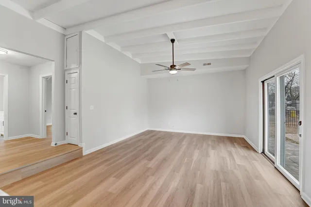 an empty room with wooden floor chandelier fan and windows