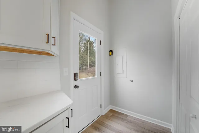 a kitchen with granite countertop a refrigerator a sink dishwasher a oven and white cabinets with wooden floor