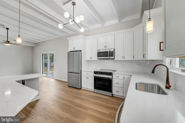 a kitchen with stainless steel appliances granite countertop a stove a sink dishwasher a refrigerator oven a stove with white cabinets and wooden floor