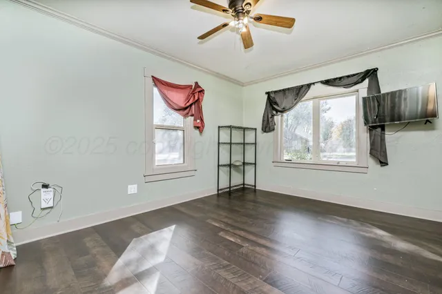 a view of an empty room with a window and wooden floor
