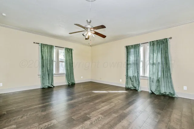 a view of empty room with wooden floor and fan