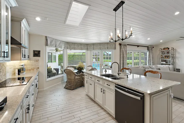 a kitchen with stainless steel appliances kitchen island granite countertop a refrigerator a stove a sink dishwasher and a dining table with wooden floor