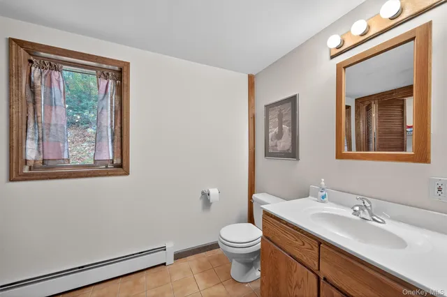 a bathroom with a granite countertop toilet a sink a mirror and a window