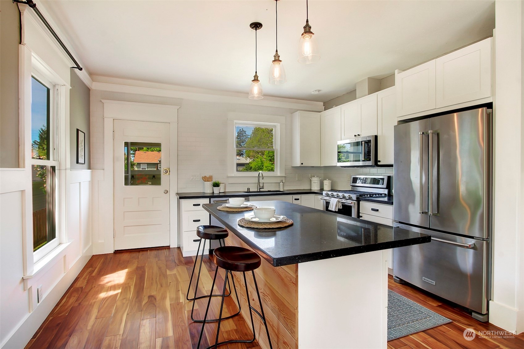 6021 48th Avenue Southwest Seattle, WA 98136 - Photo 11 of 35 a kitchen with stainless steel appliances granite countertop a refrigerator a sink dishwasher a stove and a dining table with wooden floor