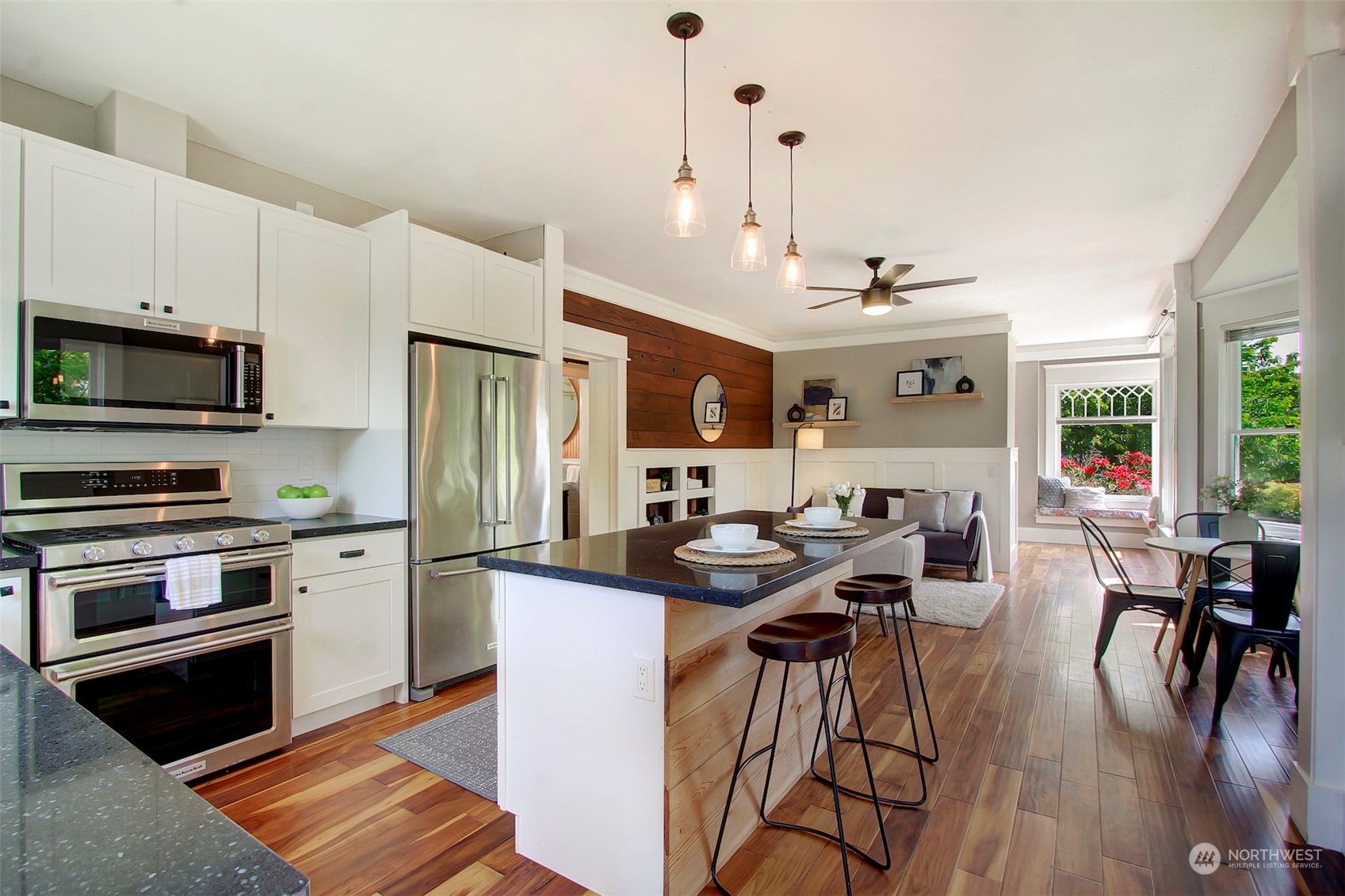 6021 48th Avenue Southwest Seattle, WA 98136 - Photo 12 of 35 a kitchen with stainless steel appliances granite countertop a stove a refrigerator a kitchen island a sink a stove and white cabinets with wooden floor