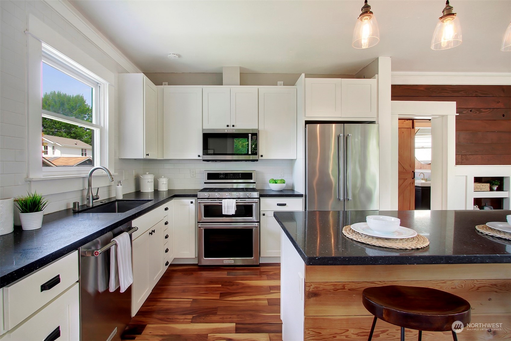 6021 48th Avenue Southwest Seattle, WA 98136 - Photo 13 of 35 a kitchen with stainless steel appliances a sink a stove a refrigerator cabinets and a dining table with wooden floor