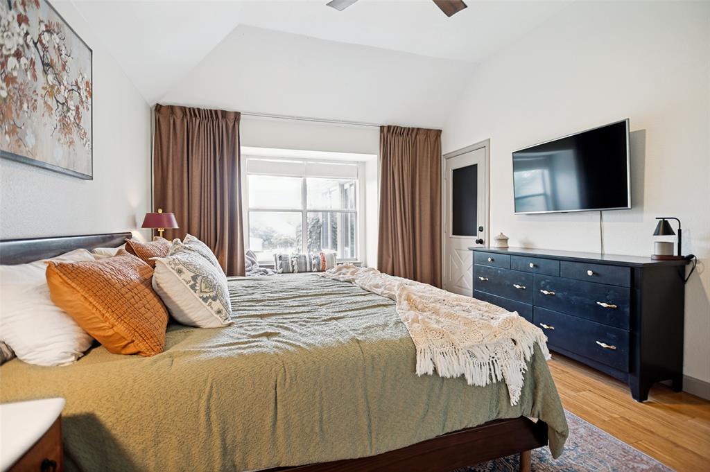 5643 West Caylor Road Fort Worth, TX 76244 - Photo 17 of 37 Vaulted ceiling bedroom featuring a bay window with natural light, wood-finish flooring, a ceiling fan, and a paneled exterior door