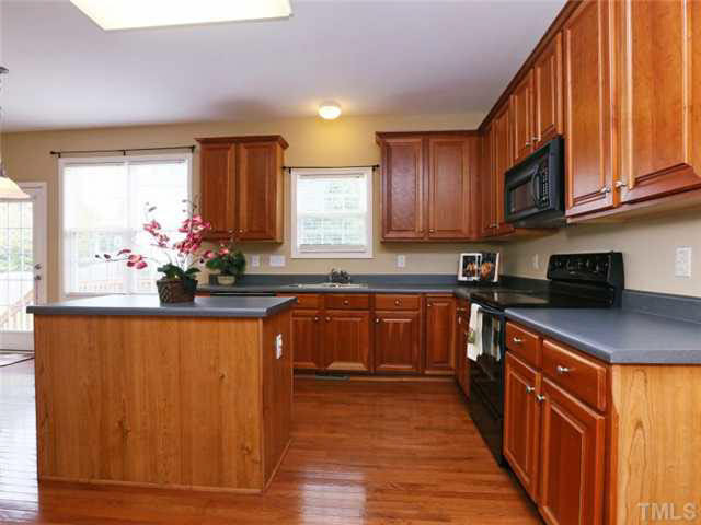 8608 Churchdown Court Raleigh, NC 27613 - Photo 7 of 25 Cherry cabinets add a richness to the kitchen. Smooth top electric range, microwave and a center island provides ample counter space. Kitchen