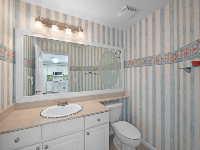 a bathroom with a granite countertop sink a toilet and a mirror