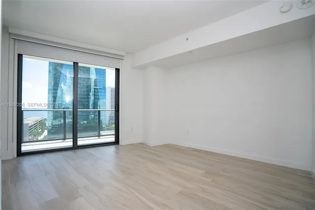 a view of an empty room with wooden floor and closet