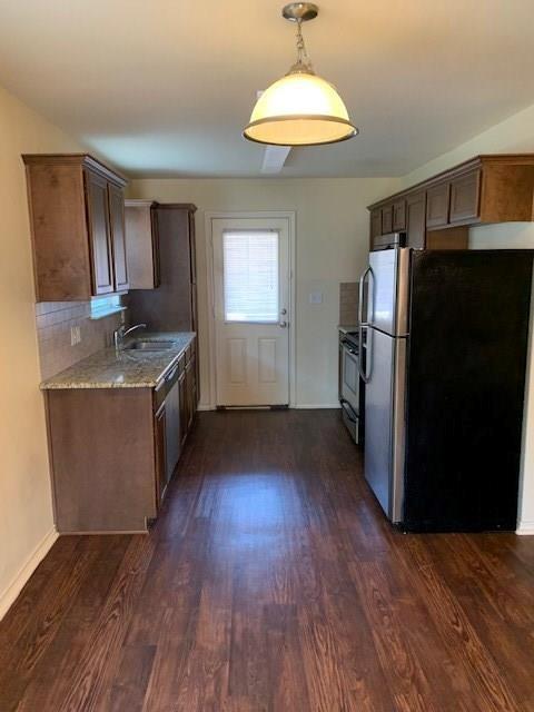 714 Parkplace Ridge Princeton, TX 75407 - Photo 5 of 15 Galley kitchen featuring wood-finish flooring, dark wood cabinetry, and a light-colored speckled countertop