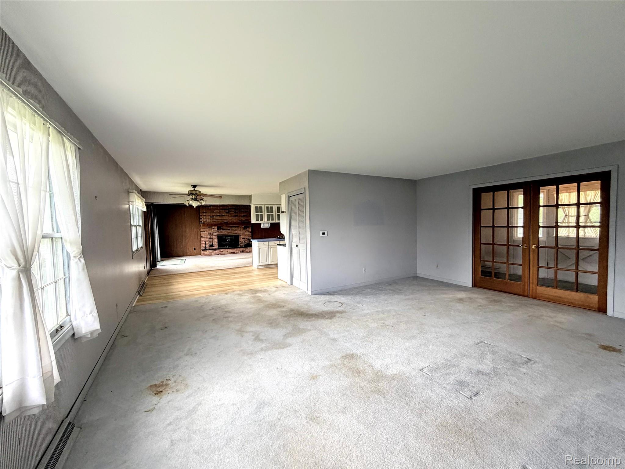 8079 Farley Road Pinckney, MI 48169 - Photo 8 of 43 Unfurnished living room with french doors, a fireplace, ceiling fan, and light carpet
