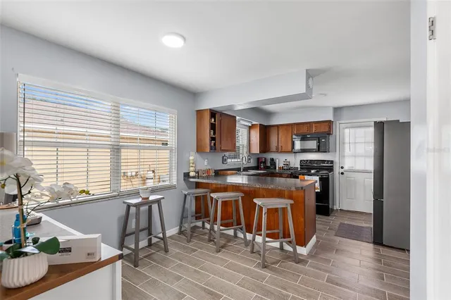 a kitchen with stainless steel appliances granite countertop a stove a refrigerator a sink a dining table and chairs