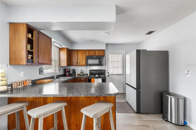 a kitchen with stainless steel appliances granite countertop a kitchen island a stove a refrigerator a stove a sink dishwasher and cabinets with wooden floor